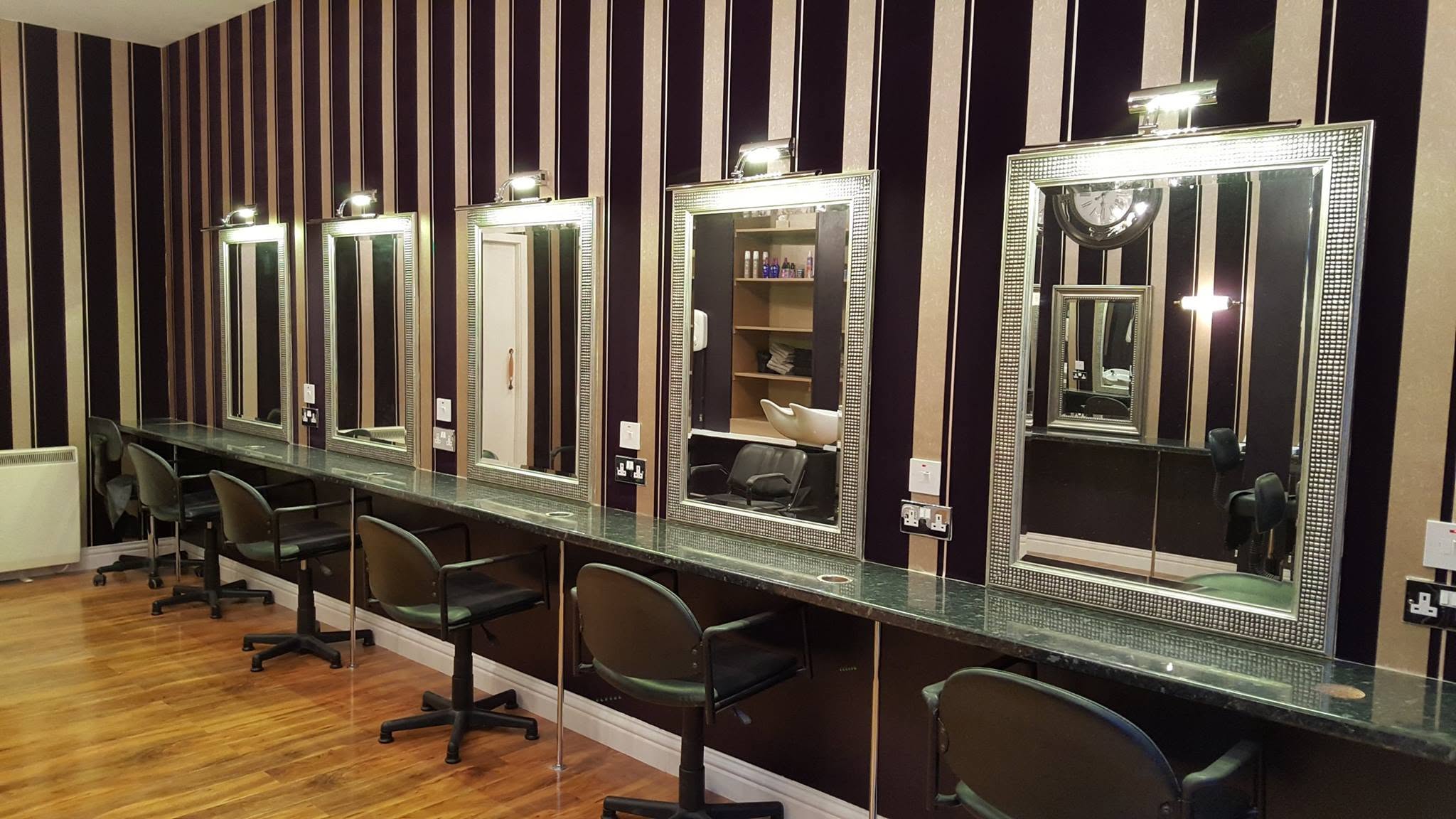 Striped wallpaper around decorative mirrors in a salon